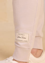 Close-up image of a grey jogger pant leg featuring a patch with the text 'ALONGE Limited Edition' and the words 'Fit. Confident. Classy,' showcasing the detailed branding in a minimalist setting.