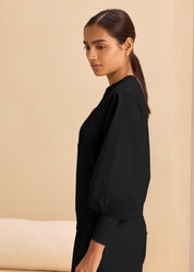 A woman in a black sweatshirt, highlighting a relaxed and trendy outfit choice.